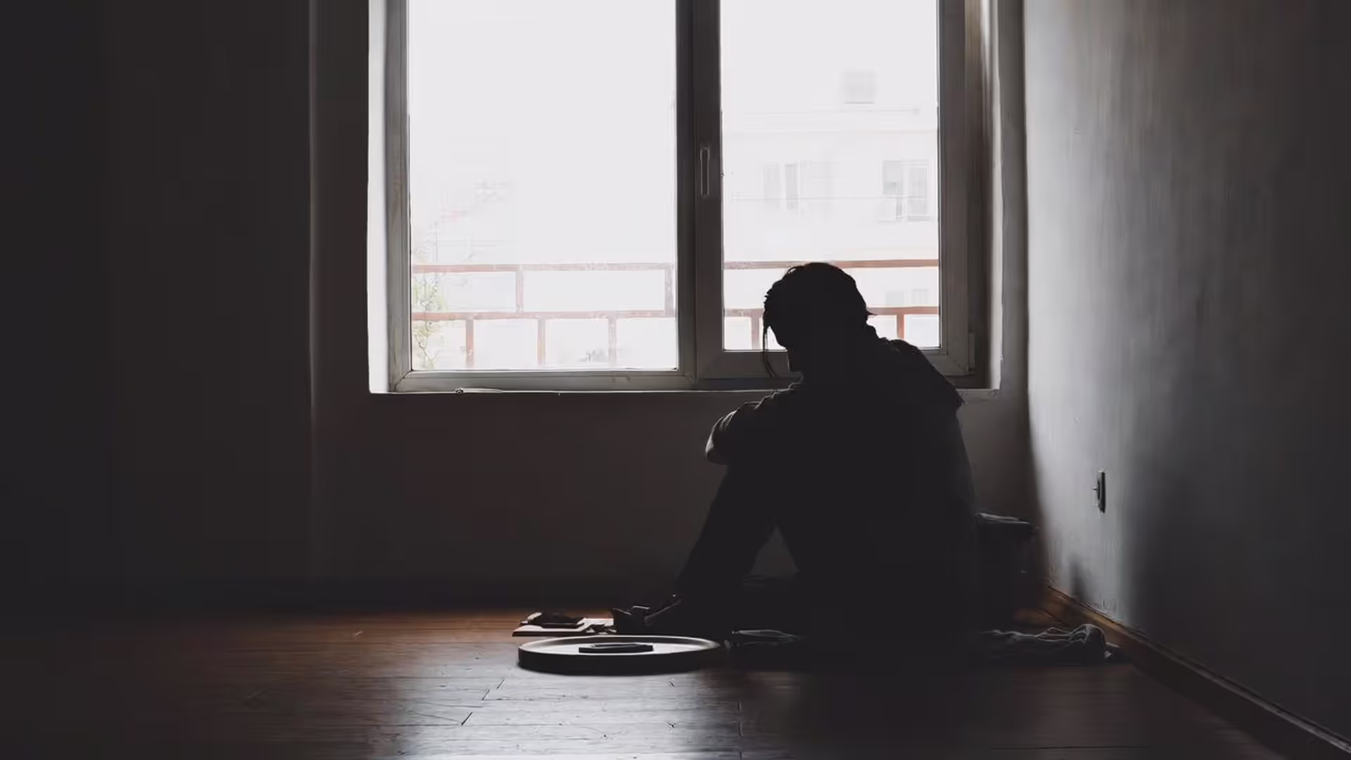 Person sitting alone at home with a phone on the table