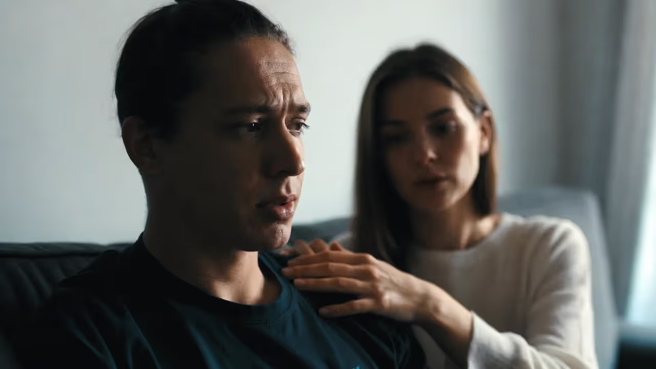 Partner offering emotional support to a stressed high achiever on a couch in a calm home setting