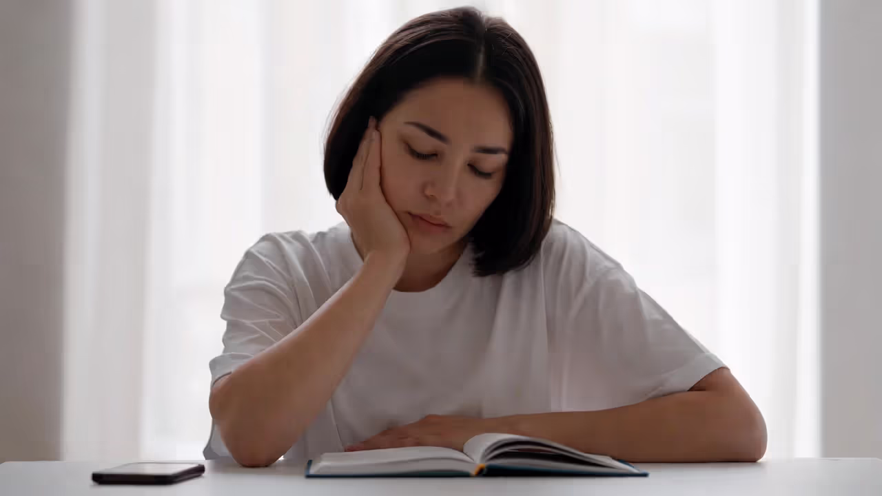 Person journaling calmly at a desk with phone placed face down